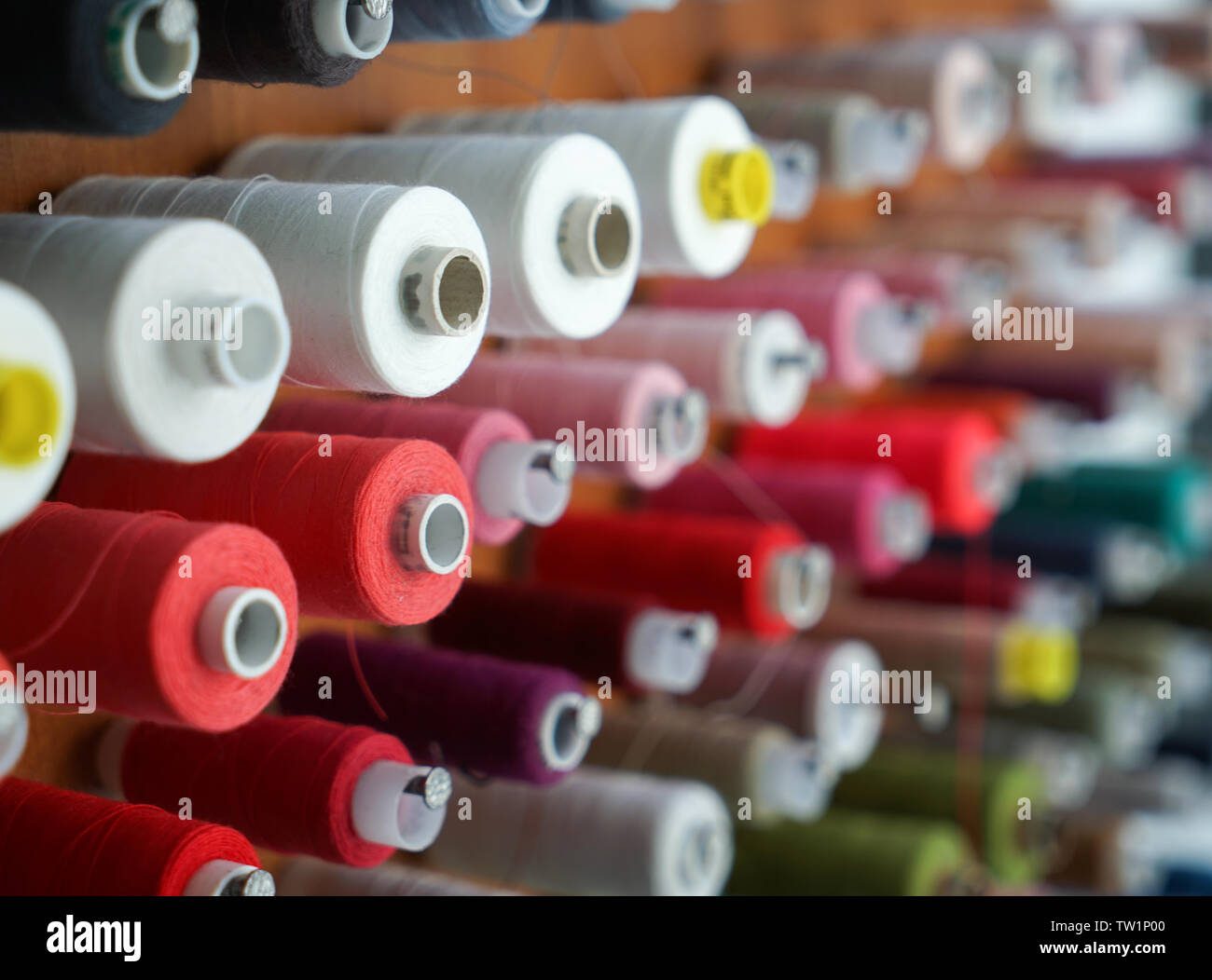 Spools with colorful threads on rack, closeup Stock Photo