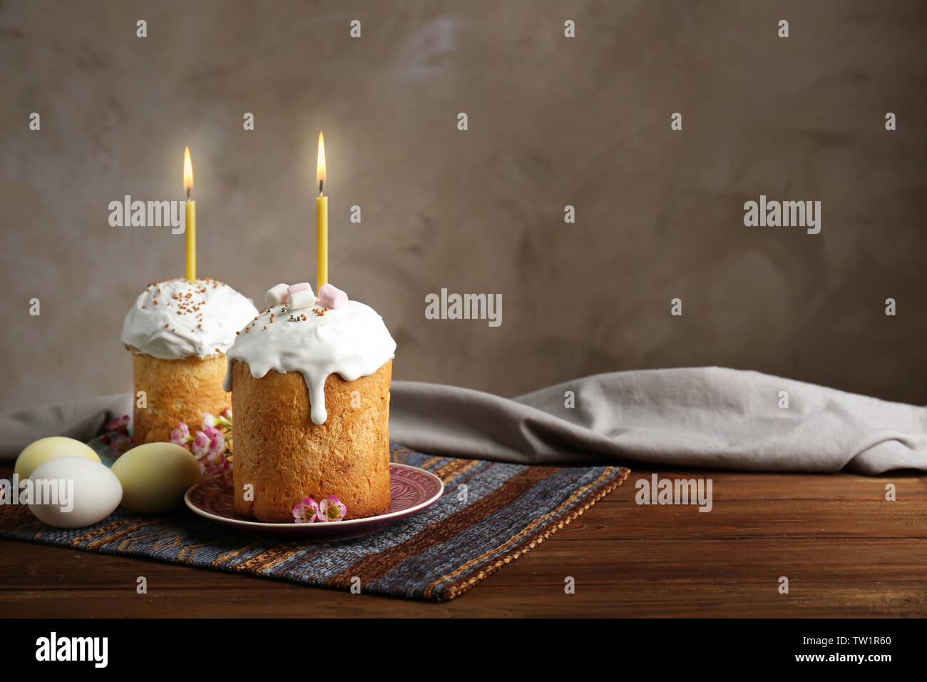 Two Easter cakes with lighted candles on wooden table Stock Photo