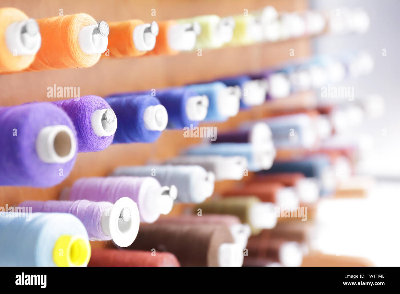 Spools with threads on rack, closeup Stock Photo