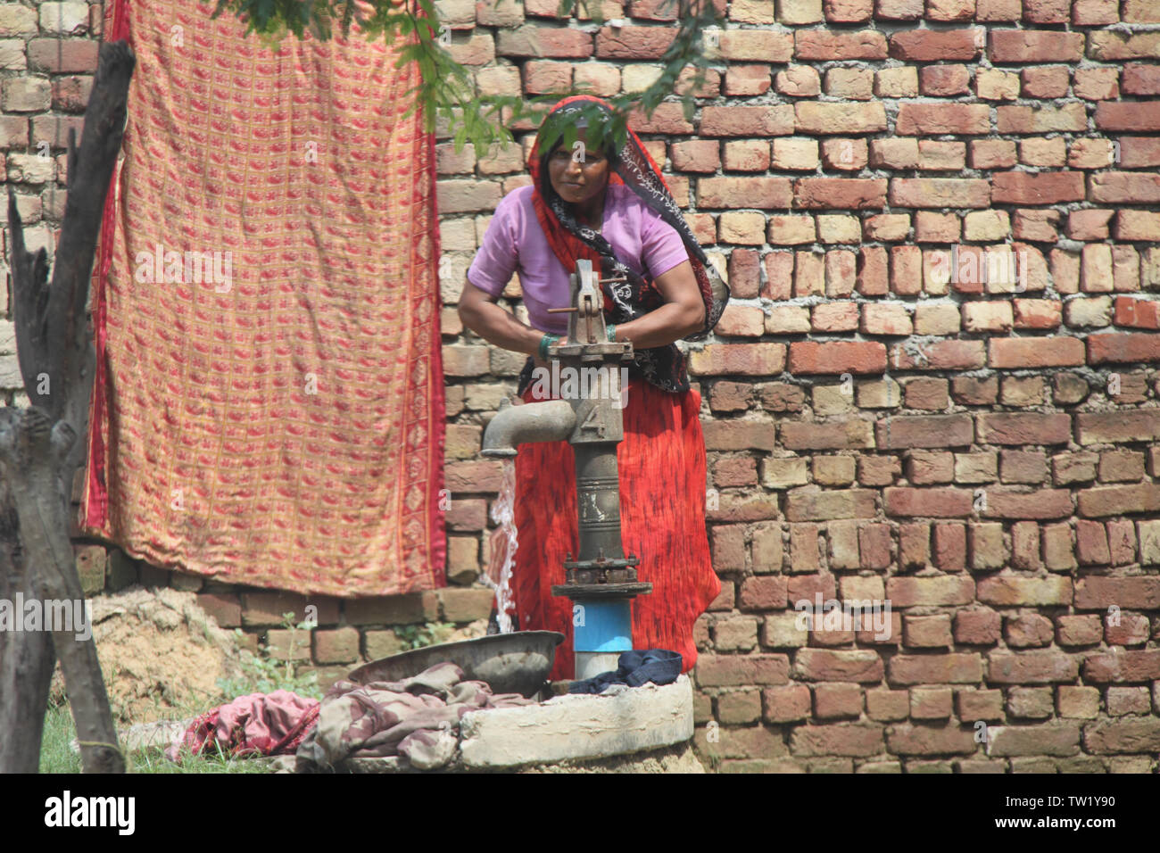 Woman drawing water from a water pump, India Stock Photo