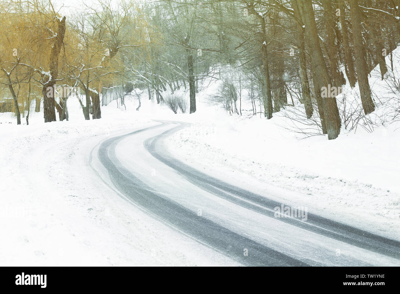 Traces of tires on snow covered road bend in winter time Stock Photo