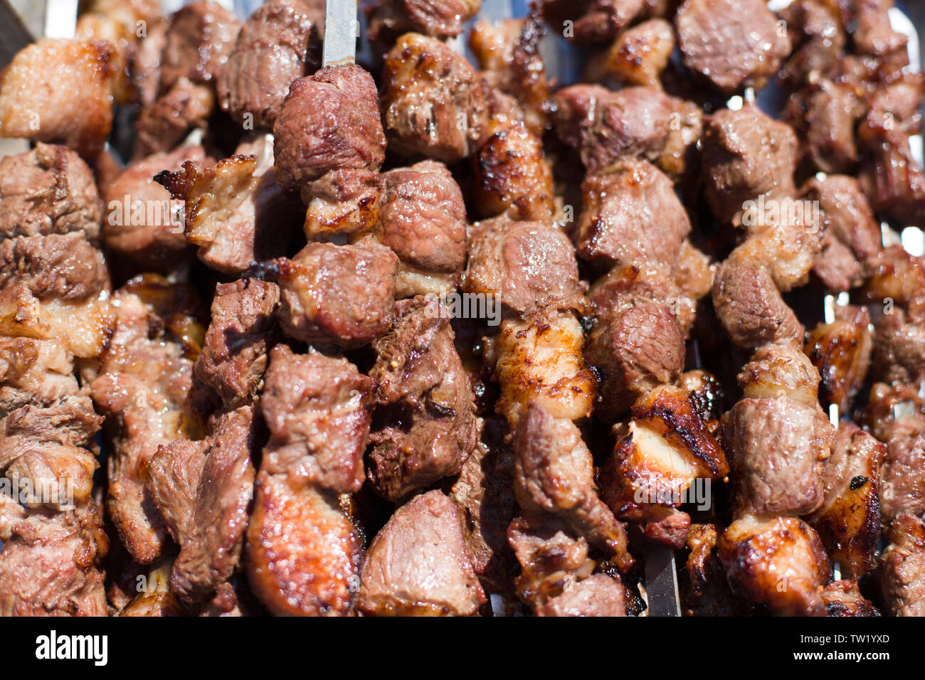 The texture of roasted meat. Appetizing cuts of meat on skewers. Grilled lamb, very tasty food. Kebab background. Stock Photo