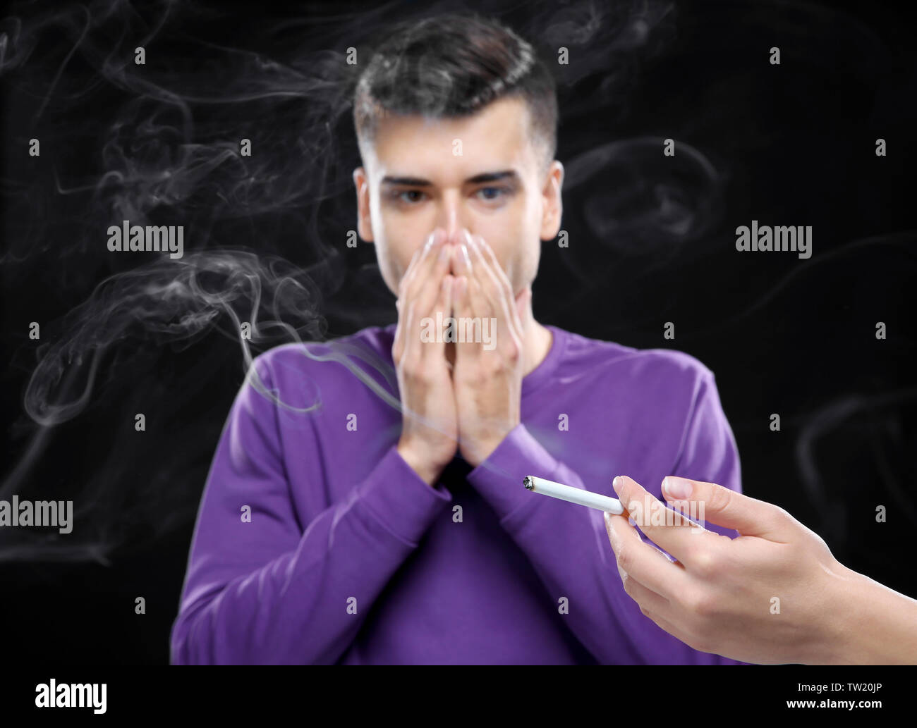 Passive smoking concept. Young man covering face from cigarette smoke