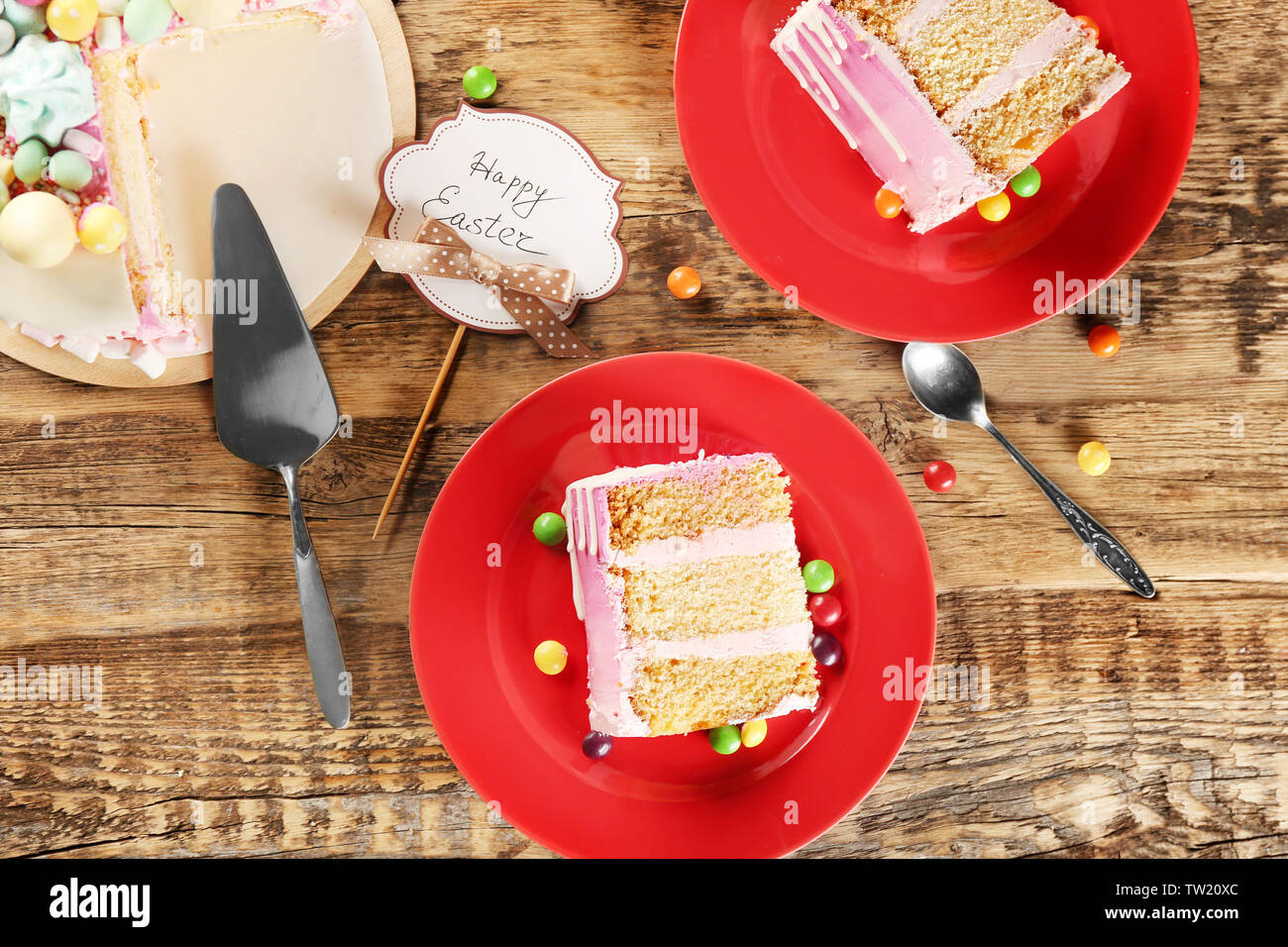 Two red plates with Easter cake slices on wooden background Stock Photo