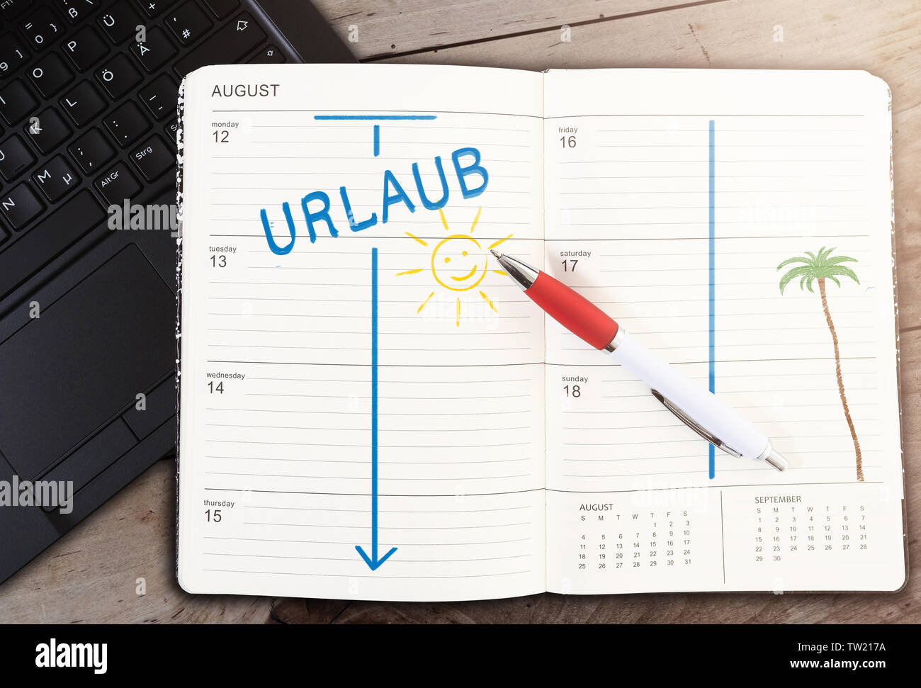 top view of calendar on table with word URLAUB, German for vacation, and sun icon against wooden table Stock Photo