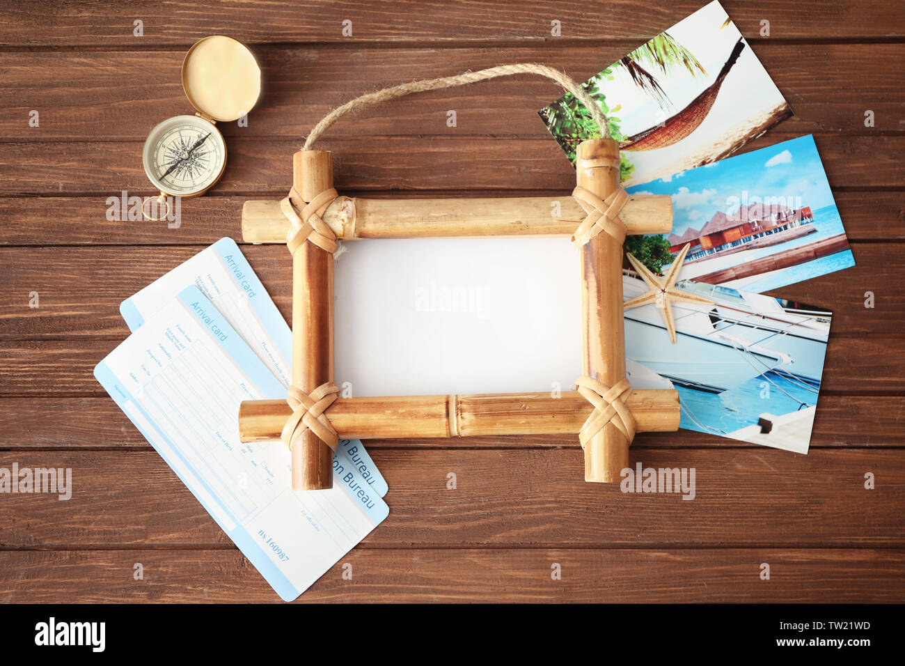 Travel concept. Bamboo frame with space for text, arrival cards and compass on wooden background Stock Photo