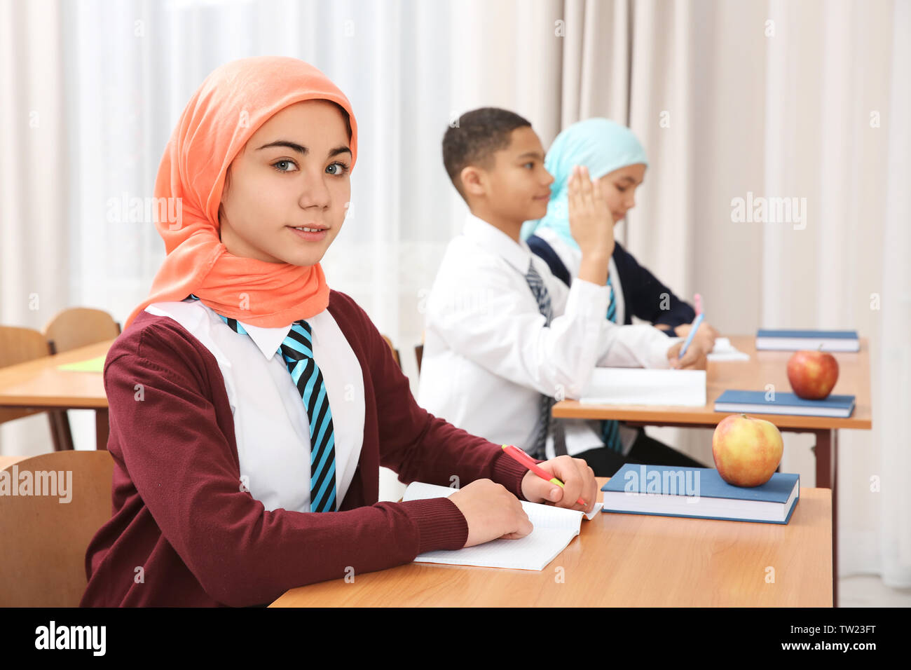 Cute girl sitting at desk in school class Stock Photo - Alamy