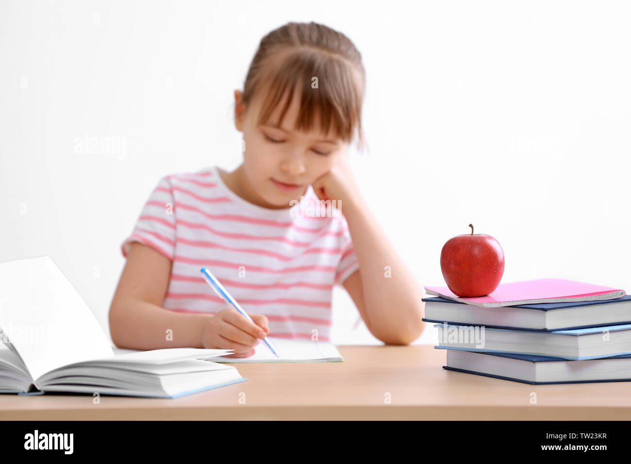 Schoolgirl studying at table on white background Stock Photo - Alamy