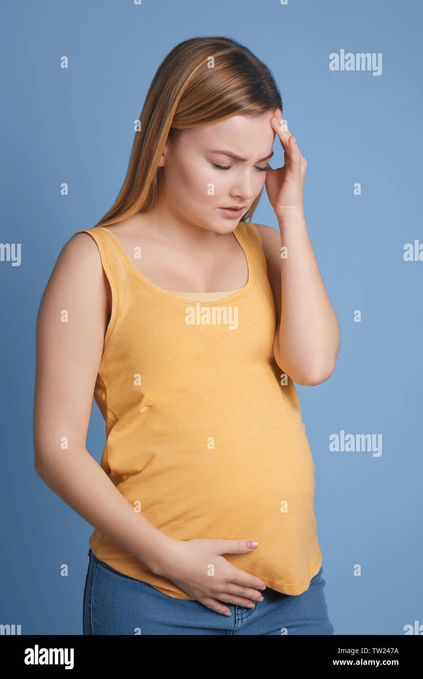 Pregnant woman suffering from headaches on blue background Stock Photo