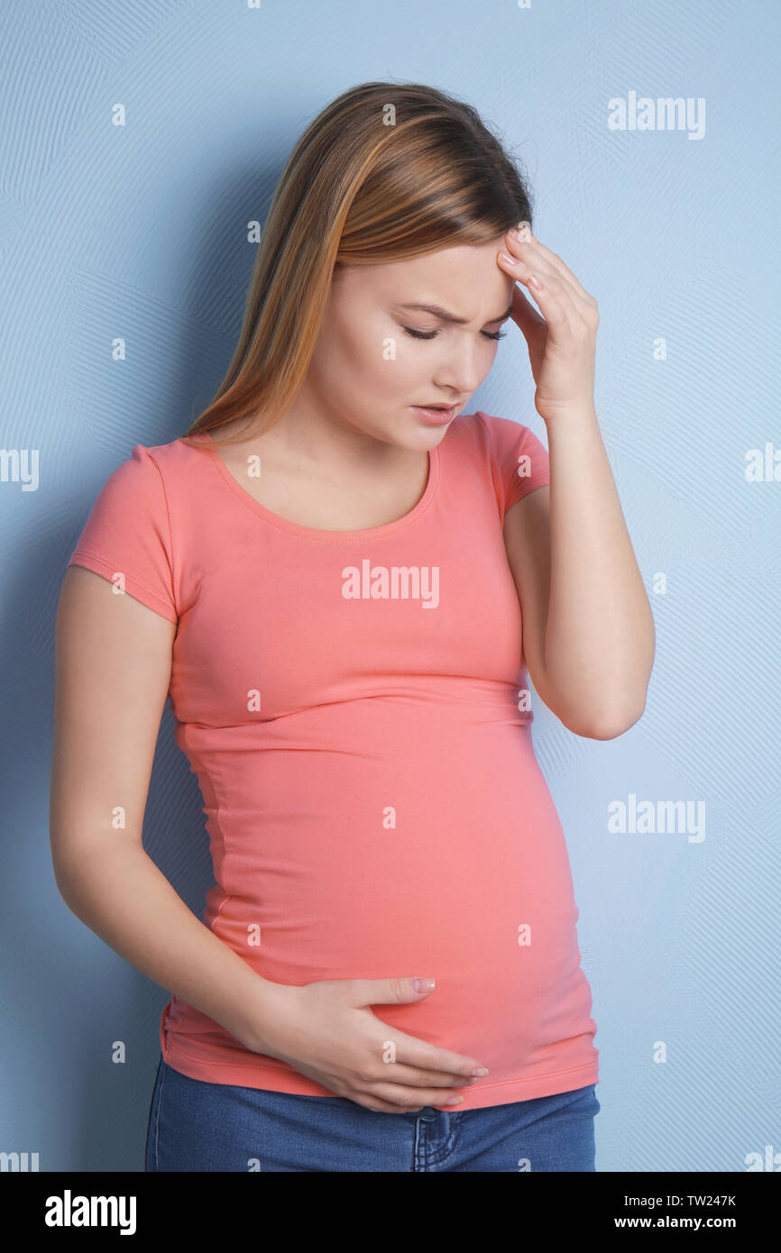 Pregnant woman suffering from headaches on blue background Stock Photo