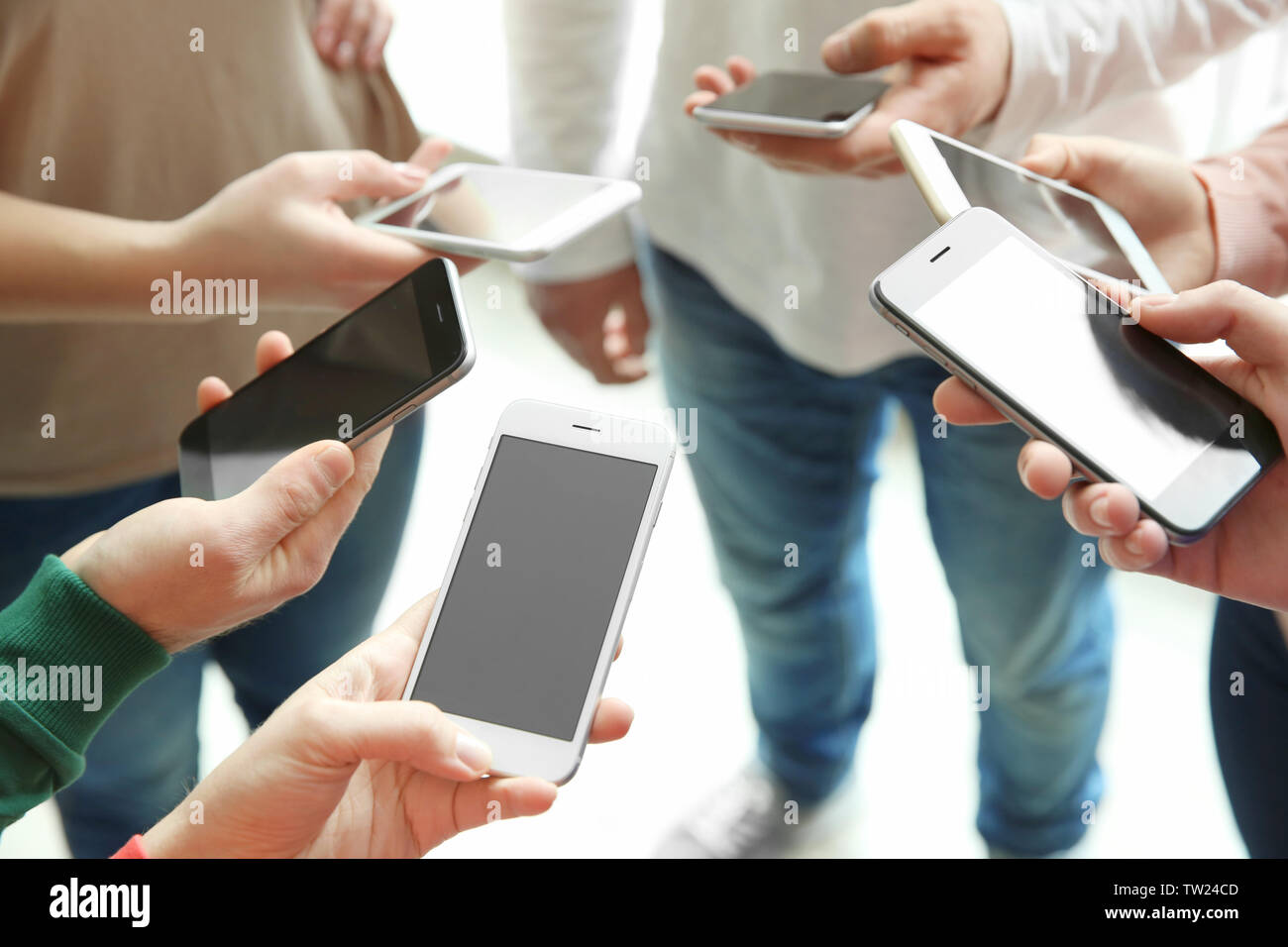 Young people standing in circle and using smartphones Stock Photo