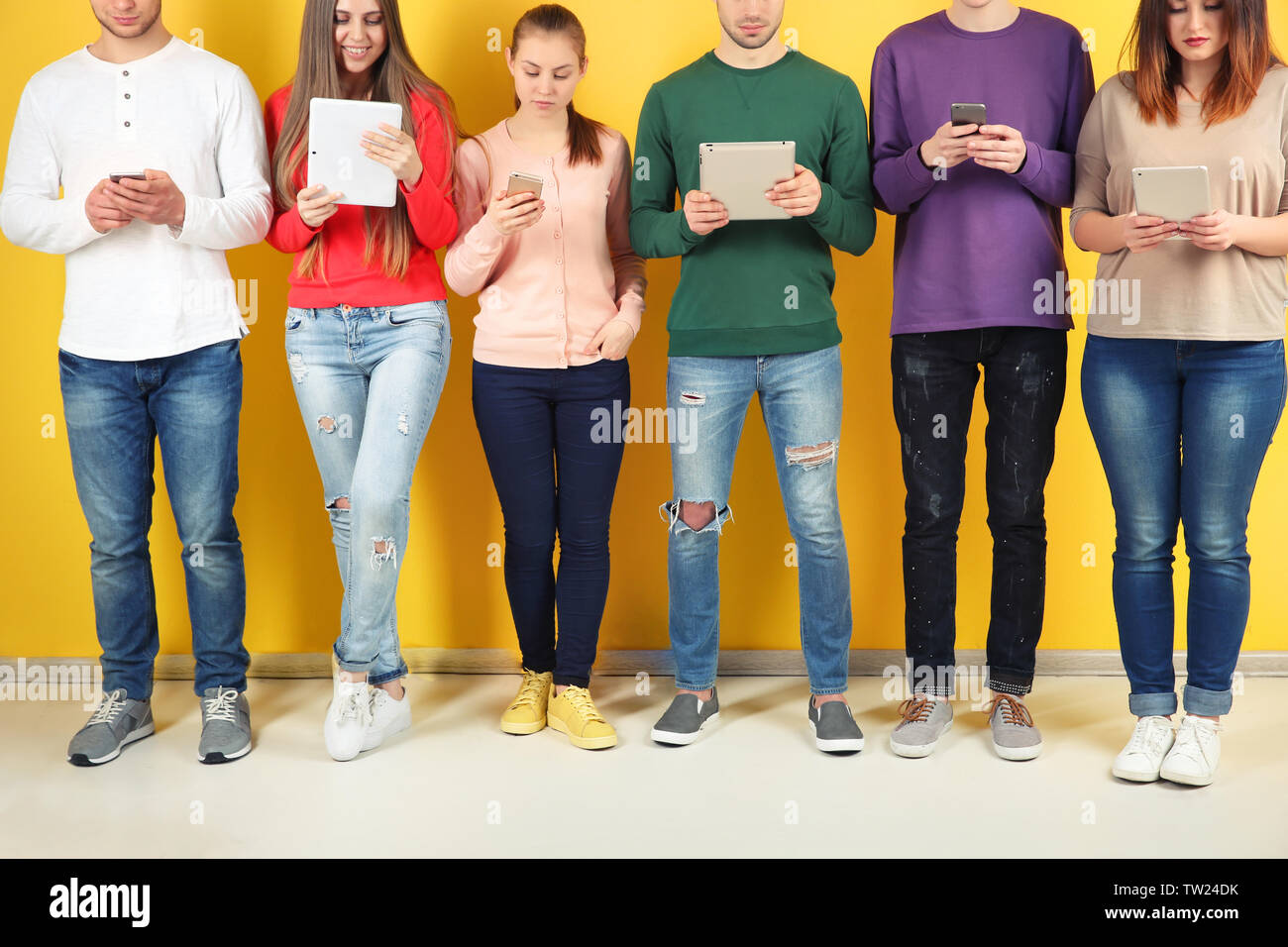 Young people using digital devices on color background Stock Photo