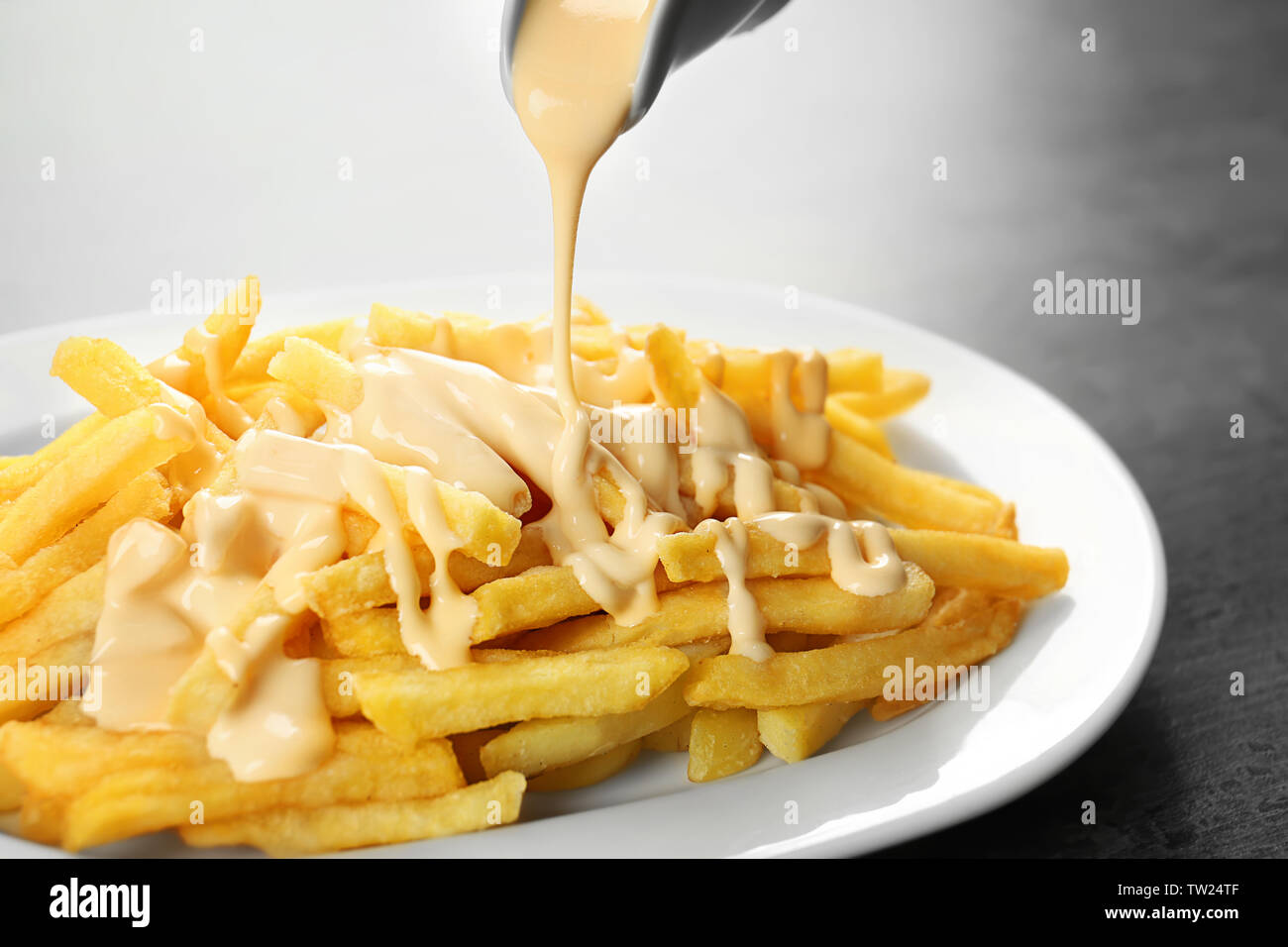 Pouring cheese sauce on french fries, closeup Stock Photo Alamy