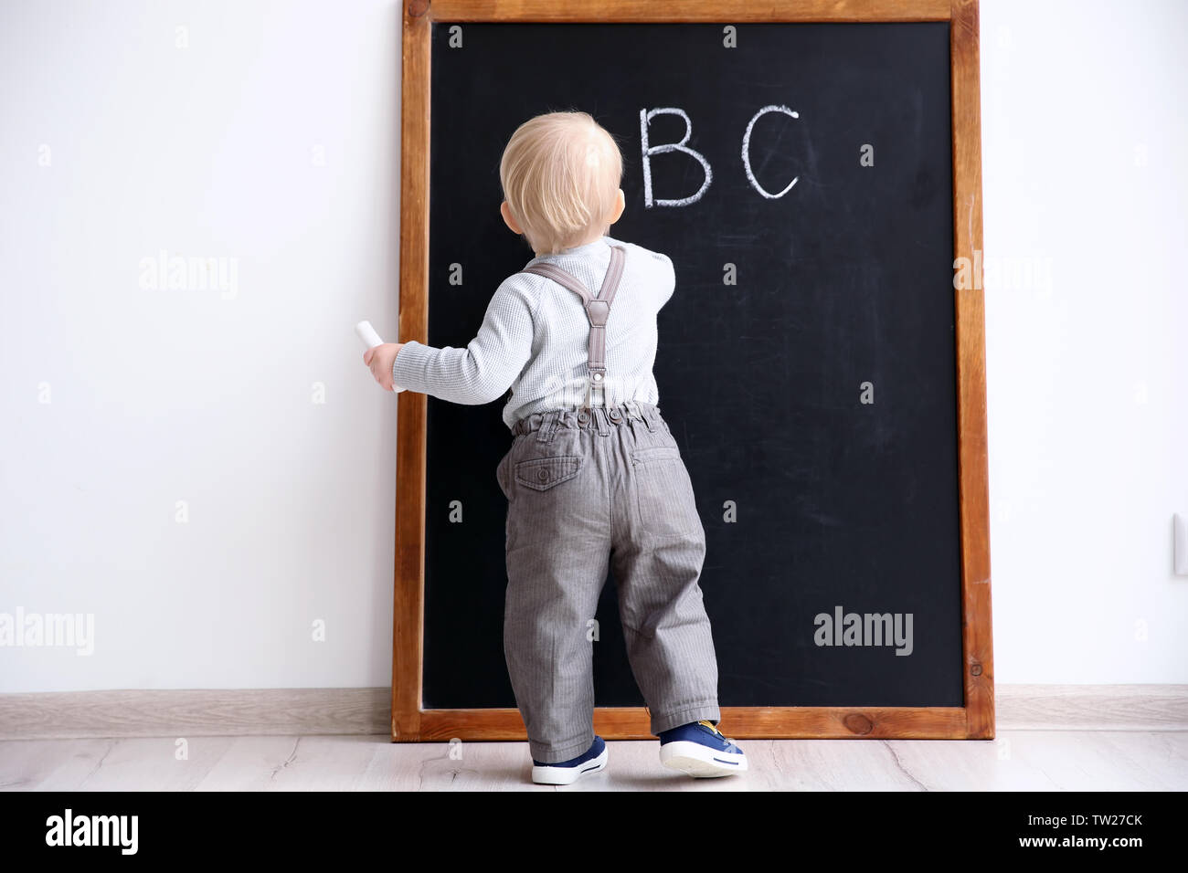 Cute little boy writing on blackboard in classroom Stock Photo - Alamy