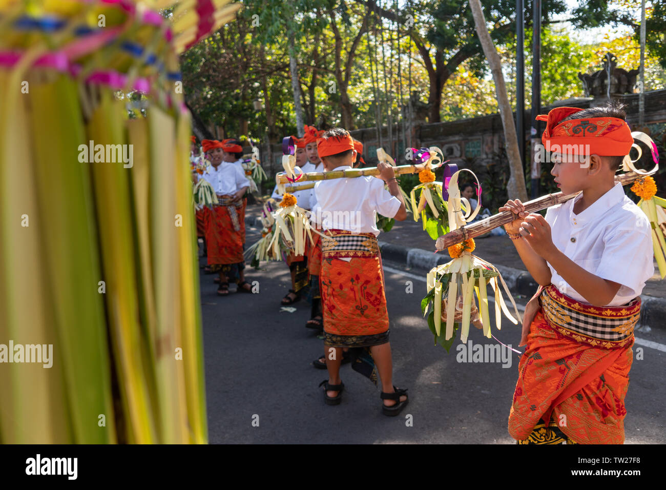 DENPASAR/BALI-JUNE 15 2019: Young Balinese boy wearing traditional Balinese headdress and traditional sarong bring sampian at the opening ceremony of Stock Photo