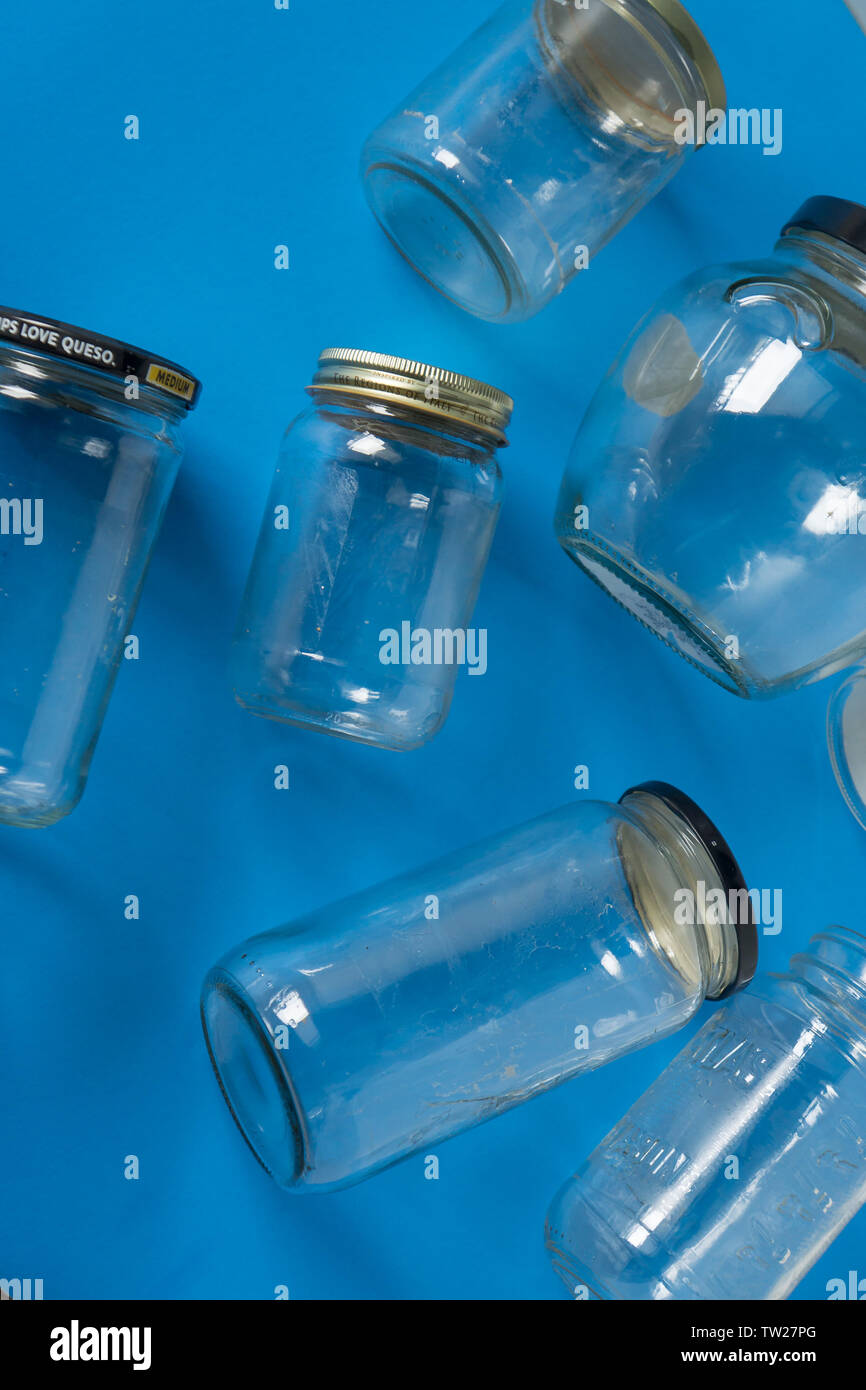 Transparent glass jars with lids isolated on blue background, top view flat lay recycling concept for environmental awareness. Segregated recyclables Stock Photo