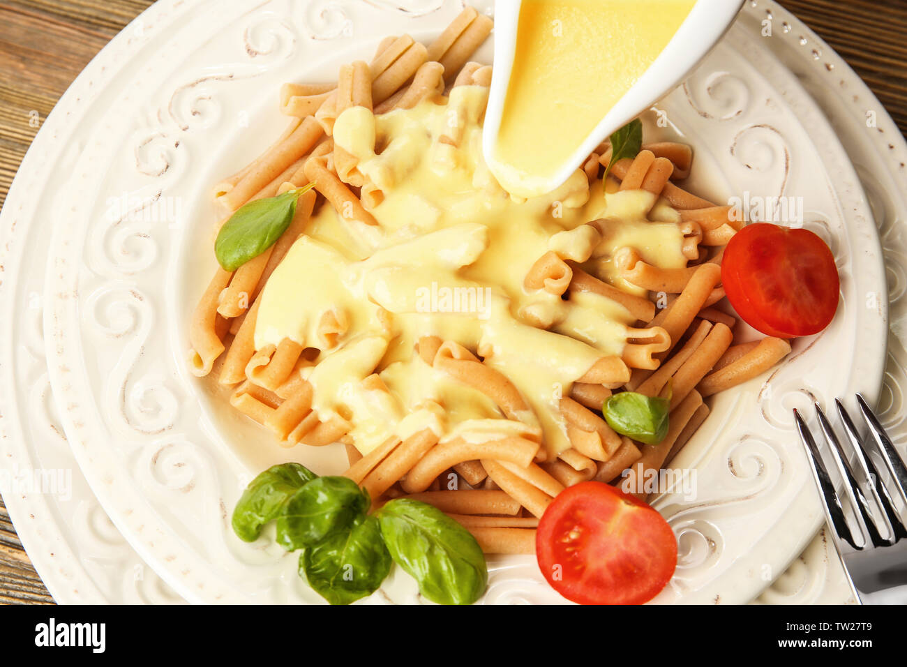 Adding cheese sauce to delicious pasta, closeup Stock Photo Alamy