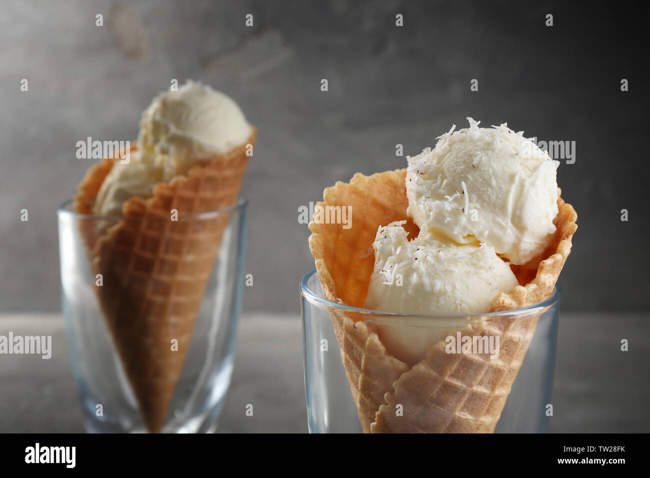 Glasses with waffle cones and balls of coconut ice cream on grunge background Stock Photo
