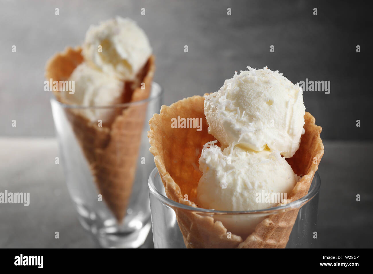 Glasses with waffle cones and balls of coconut ice cream on grunge background Stock Photo