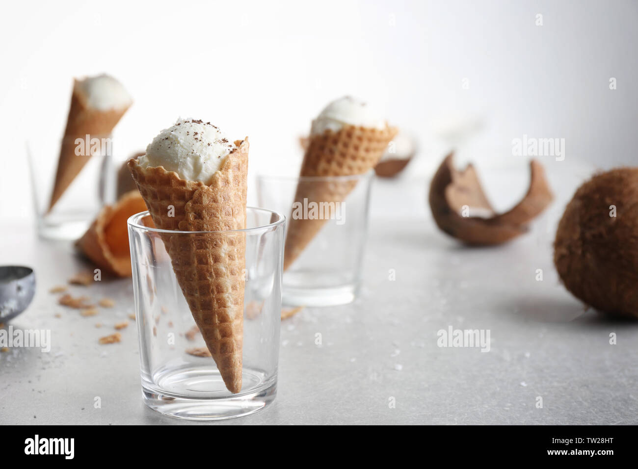 Waffle cone with ball of coconut ice cream in glass on table Stock Photo