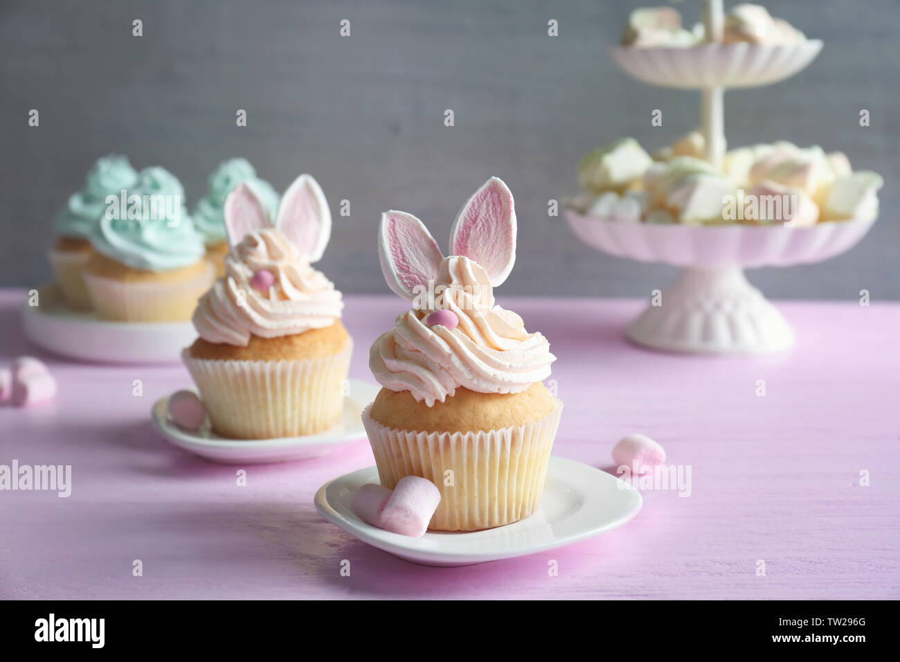 Tasty Easter cupcakes on pink wooden table against grey background Stock Photo