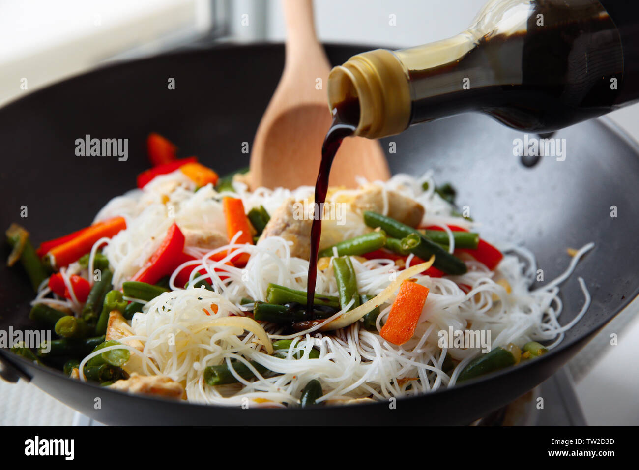 Adding soy sauce to rice noodle with vegetables in wok Stock Photo - Alamy
