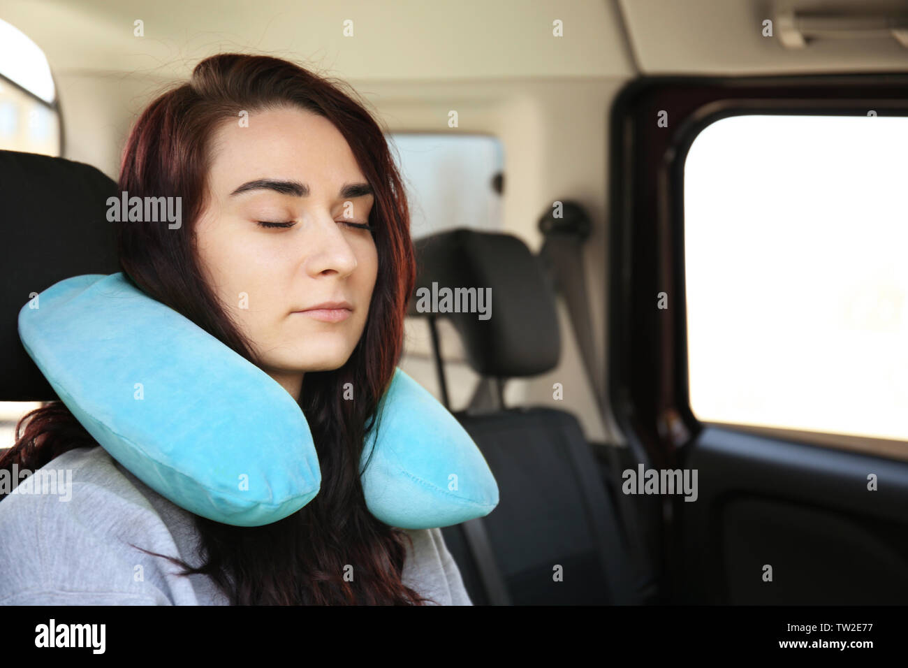 Beautiful young woman with travel pillow sleeping in car Stock Photo