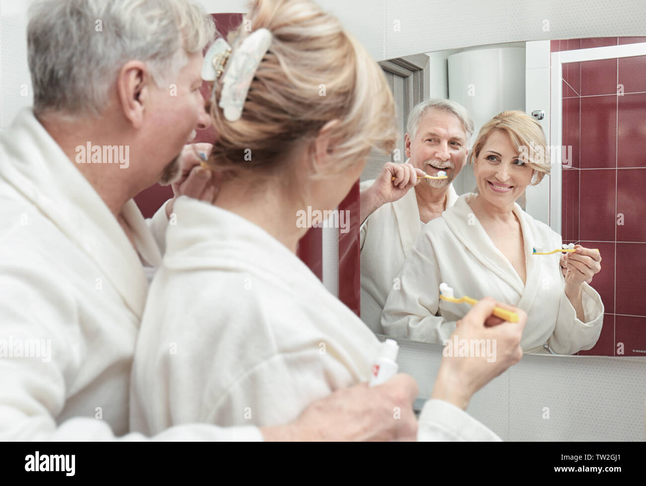 Elderly couple brushing teeth in bathroom Stock Photo