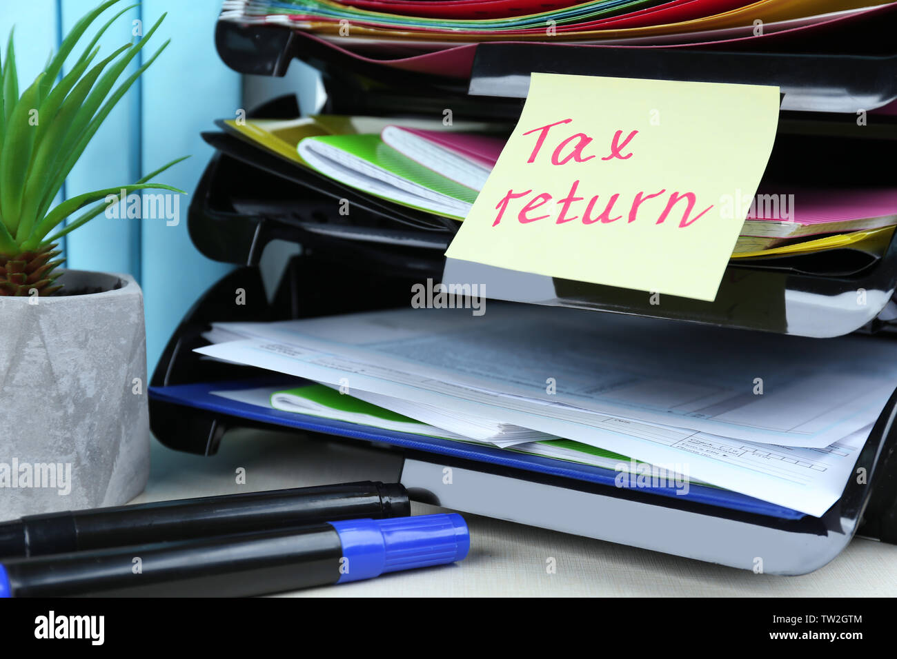 Note with TAX RETURN text, forms and stationery on table Stock Photo