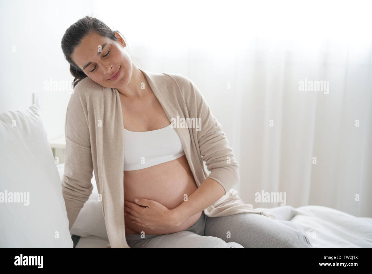 Portrait of pregnant woman relaxing on bed Stock Photo
