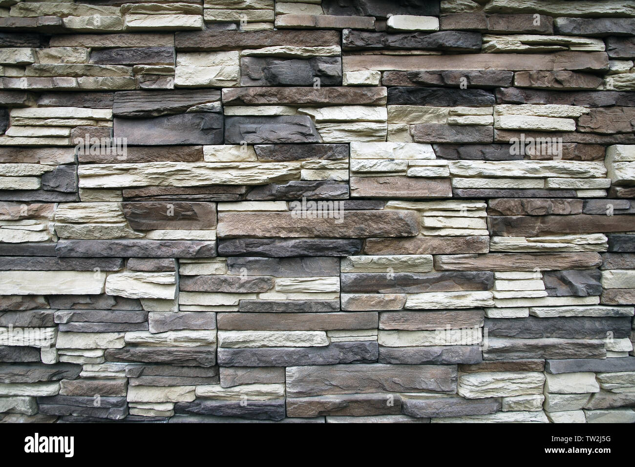Stone wall texture background of narrow flat stones in brown, gray,beige colors Stock Photo