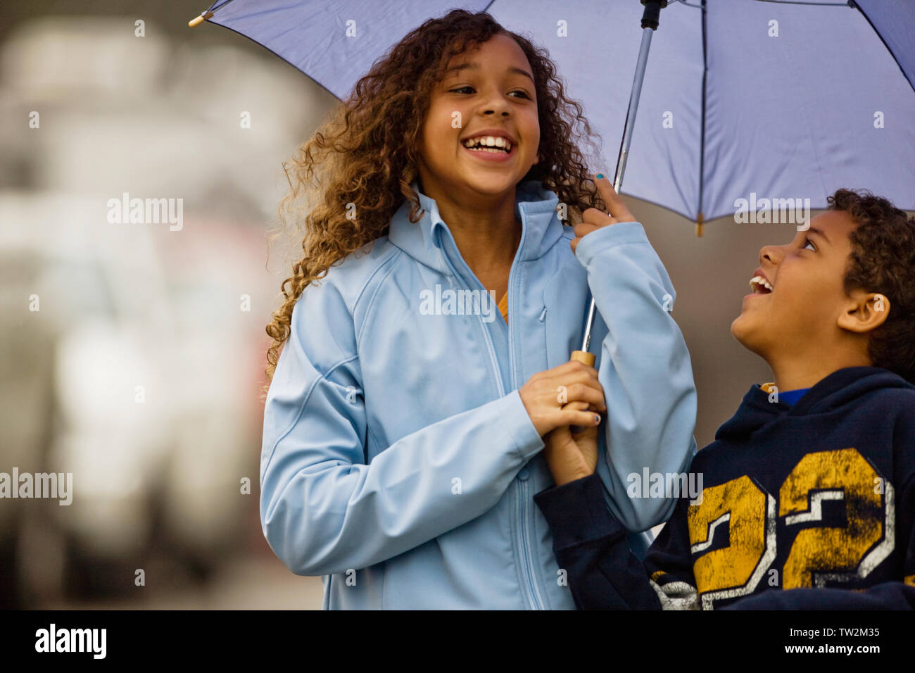 Young girl and boy holding umbrella and laughing Stock Photo Alamy