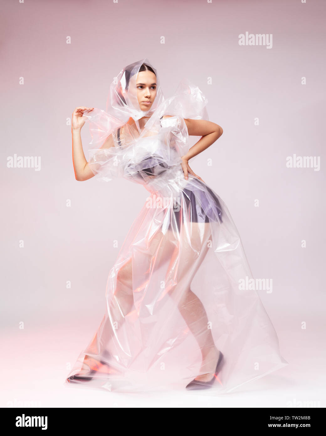 Girl posing in a dress made of plastic film. Fashion portrait. The concept of using artificial materials in clothing, environmental pollution with pol Stock Photo