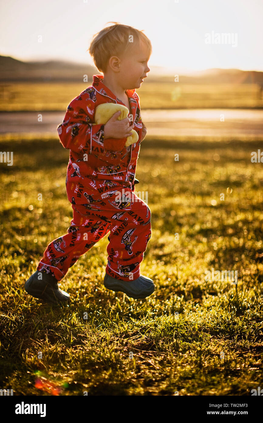 Little boy in his pyjamas running on field at sunset Stock Photo Alamy