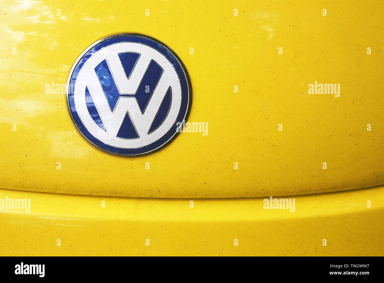 White and blue w symbol imitating Volkswagen icon on  shabby yellow hood of fake Chinese replica of Volkswagen Beetle car. Stock Photo