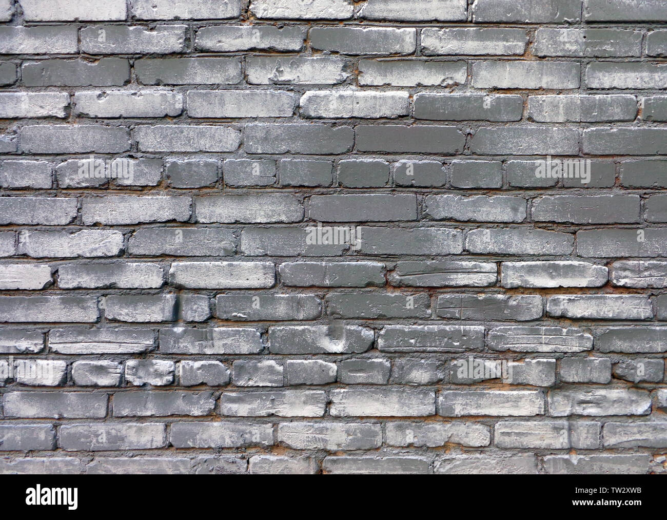 Uneven old brick wall gray painted with dark areas and white dapples, urban grunge background Stock Photo
