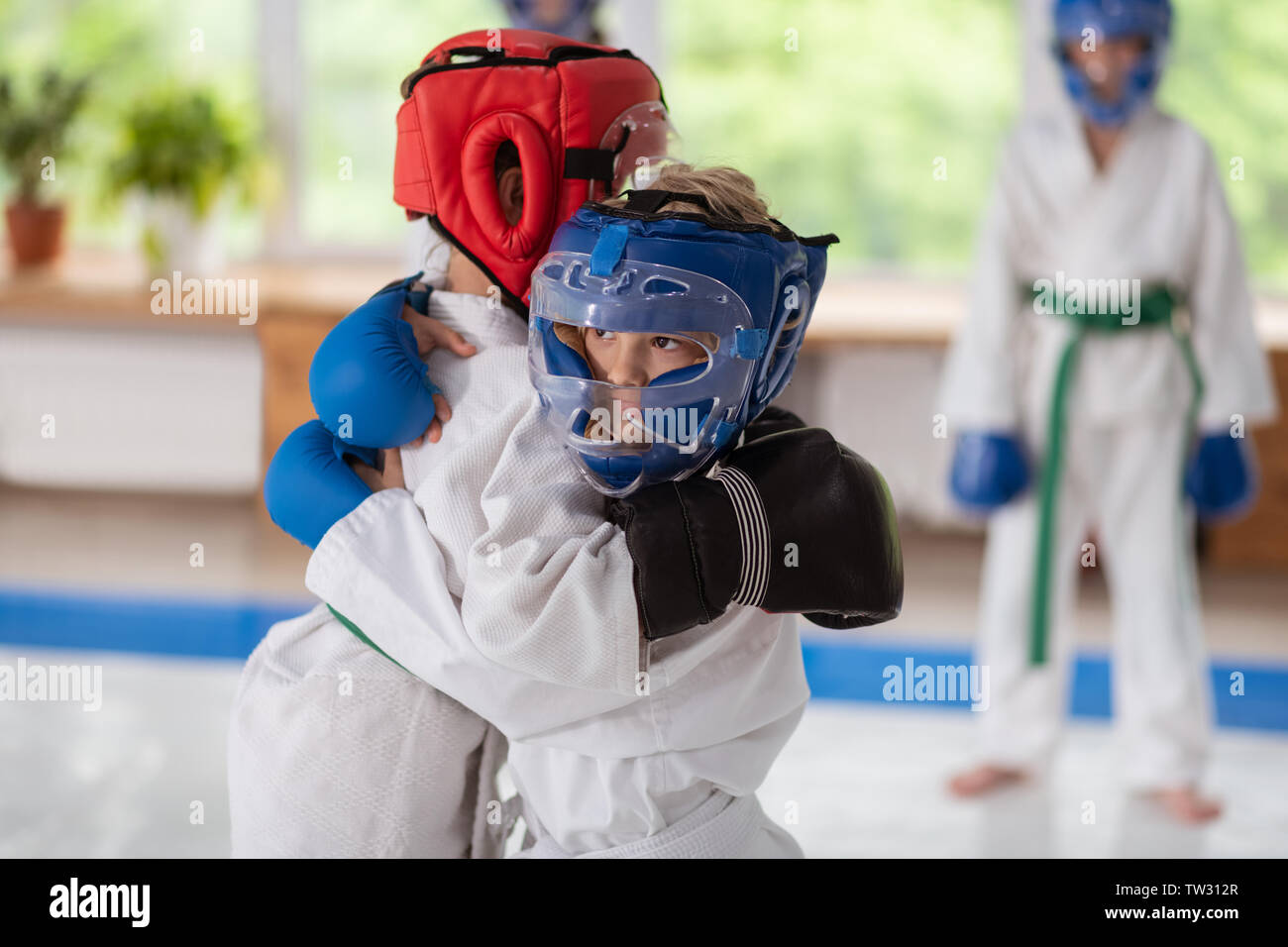 Hugging after fight. Boy and girl wearing protective helmets and white kimono hugging Stock Photo