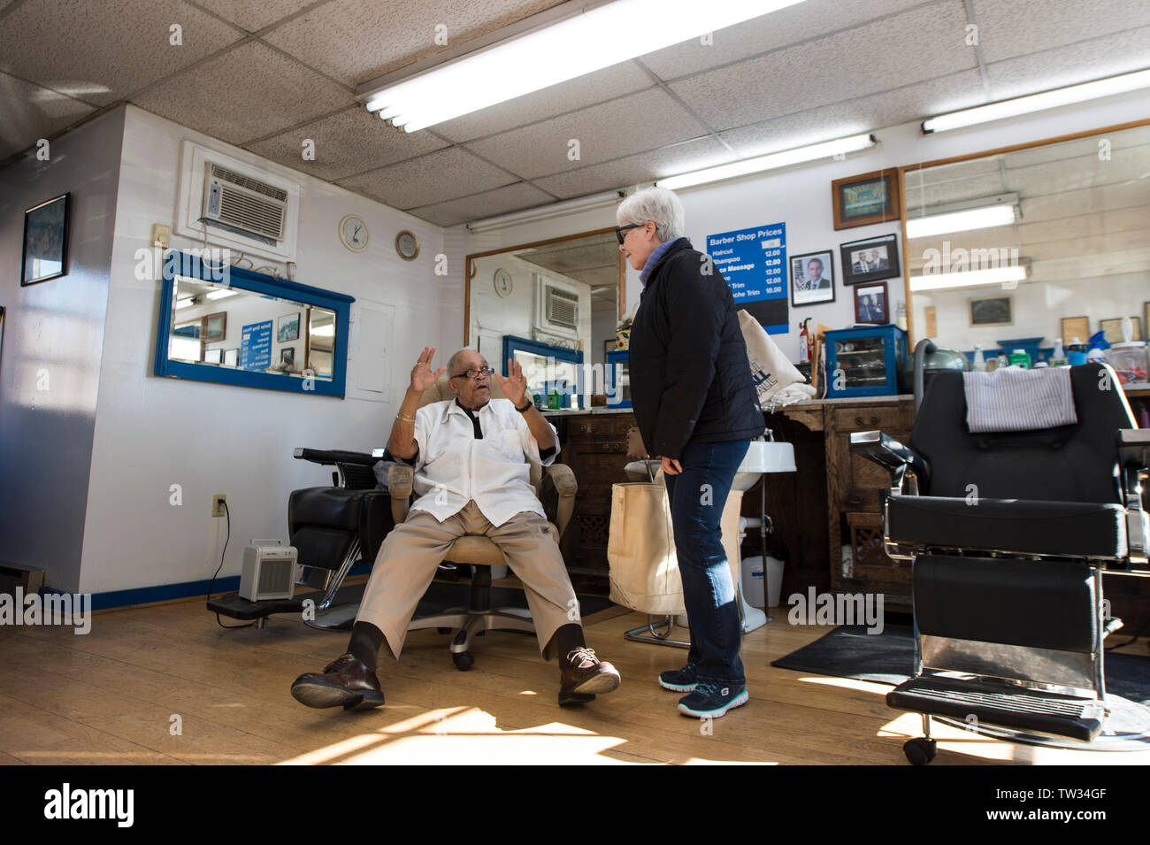 UNITED STATES - November 16. 2015: Nelson Lassiter talks with a patron at his barber shop in downtown Leesburg Virginia. The photo was taken for a fea Stock Photo