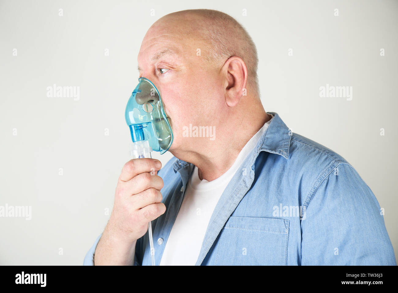 Senior man using asthma machine on light background Stock Photo