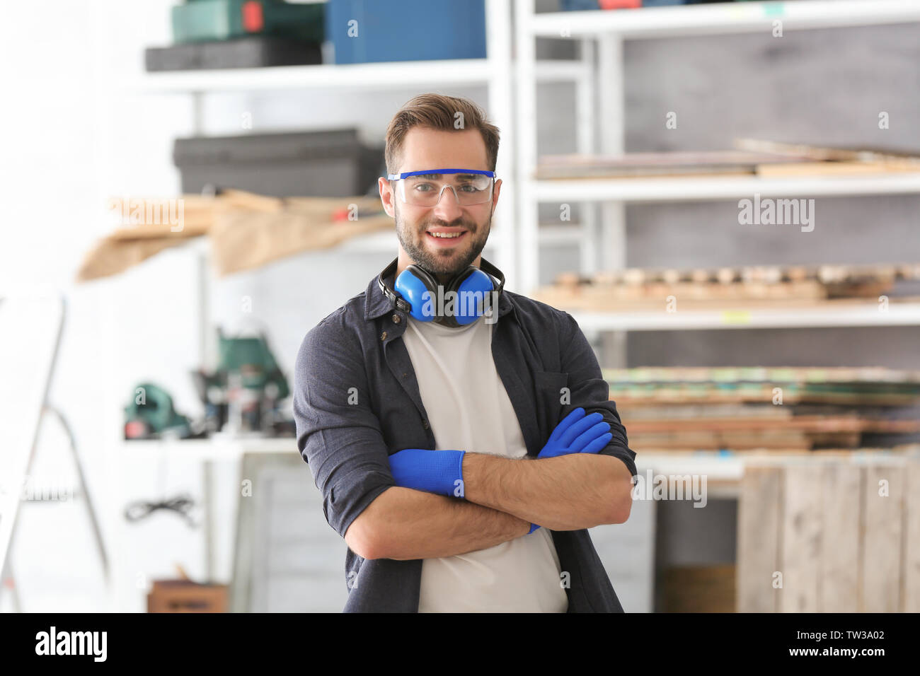 Young smiling carpenter standing with crossed hands in workshop Stock Photo