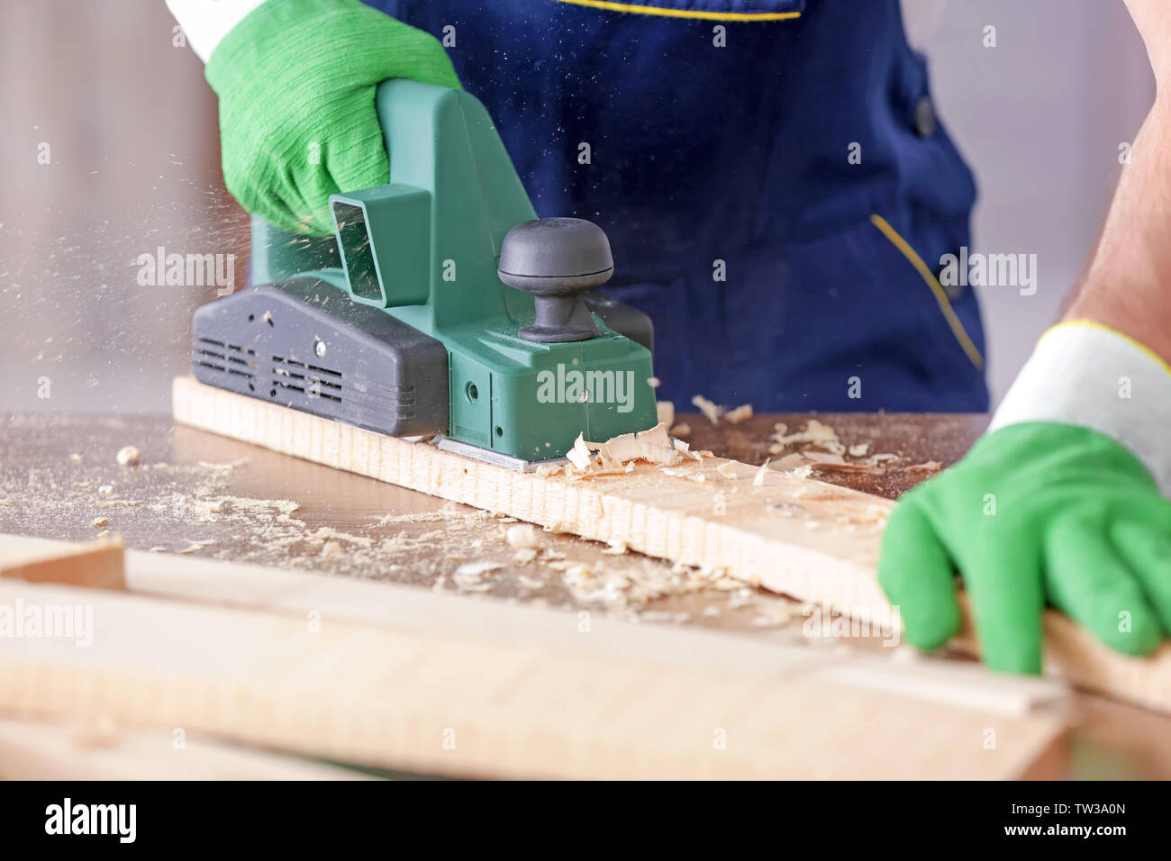 Carpenter working with electric plane, closeup Stock Photo