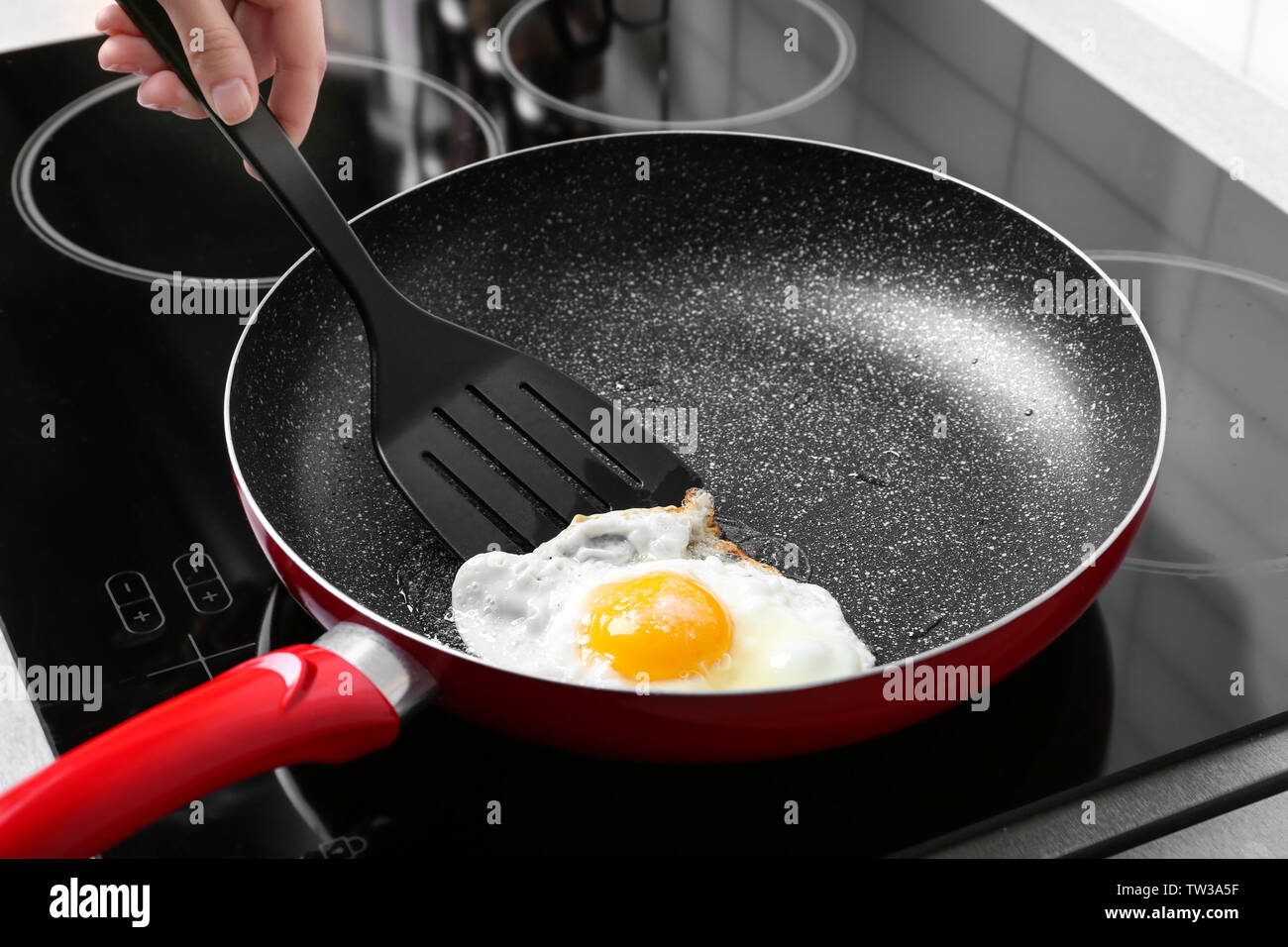 Hand of woman cooking over hard fried egg using spatula Stock Photo - Alamy