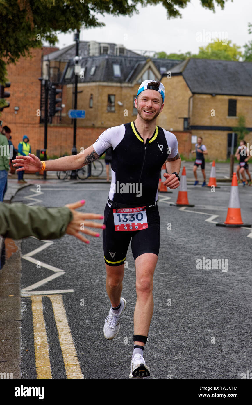 Smiling runner at the Royal Windsor Triathlon High Fives the spectators as he nears the end of this gruelling test of fitness Stock Photo