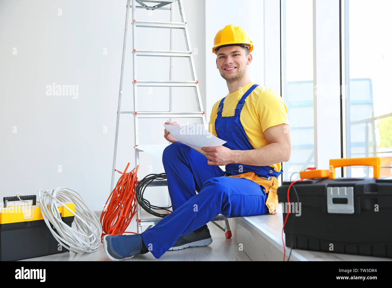 Young electrician checking scheme indoors Stock Photo