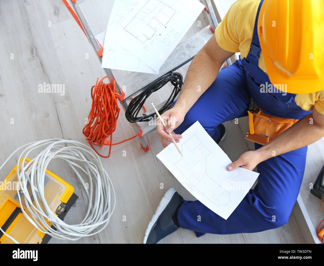 Professional electrician checking scheme indoors Stock Photo