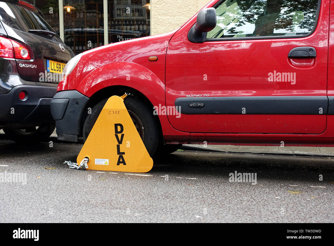 An un taxed vehicle is clamped on a street by the DVLA. The clamp is clearly marked and on the front wheel.for non payment vehicle excise duty Stock Photo