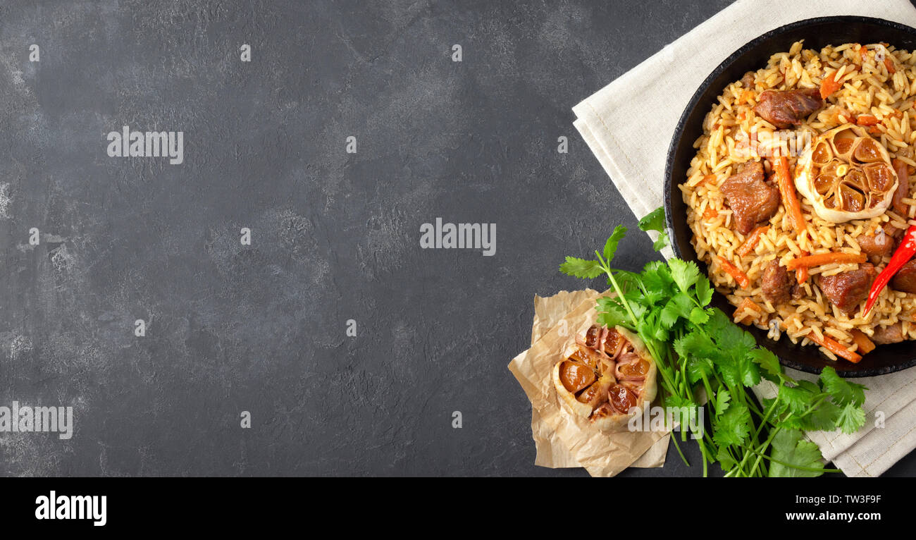 Oriental cuisine. Uzbek pilaf or plov from rice and meat in a cast iron pan. Top view vith copy space. Stock Photo