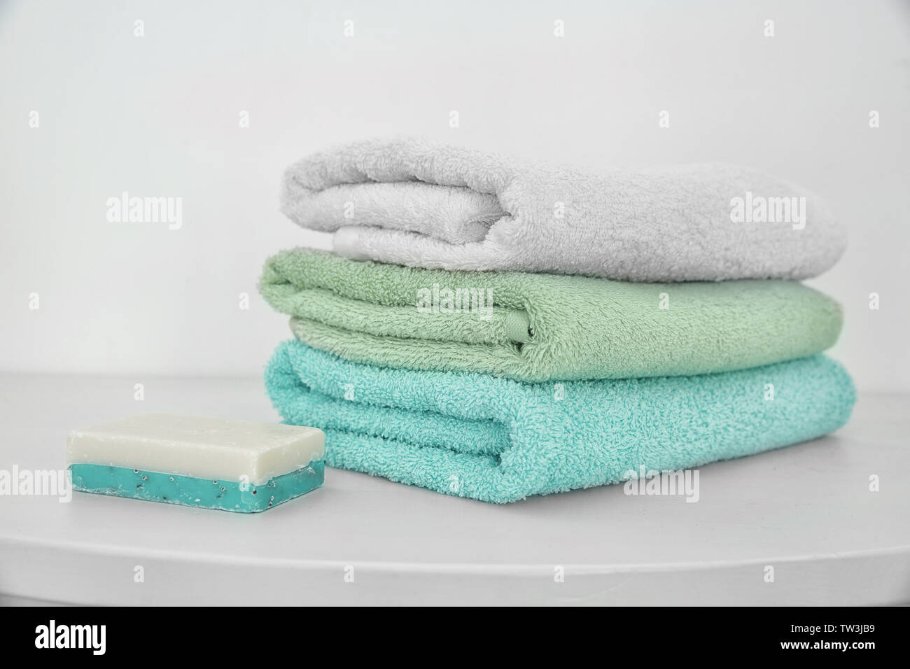 Stack of clean towels and soap on table Stock Photo