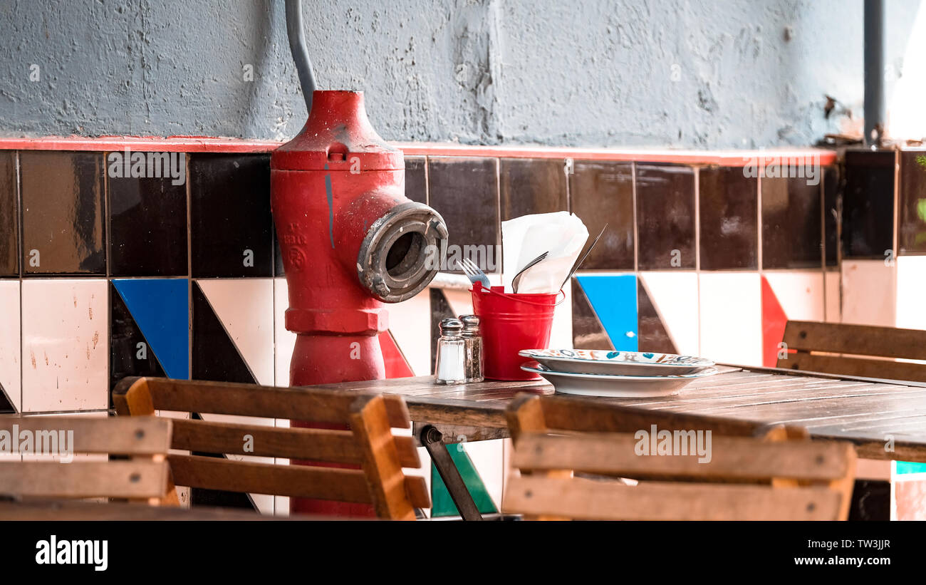 Typical serving suggestion, a fire hydrant funnily facing a restaurant table, Tel Aviv, Israel. Stock Photo