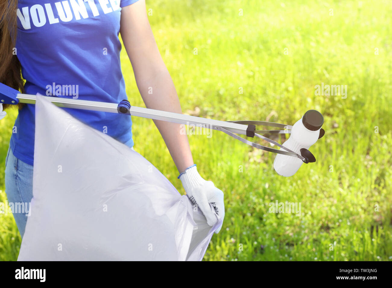 Young person gathering garbage with trash picker. Volunteering concept